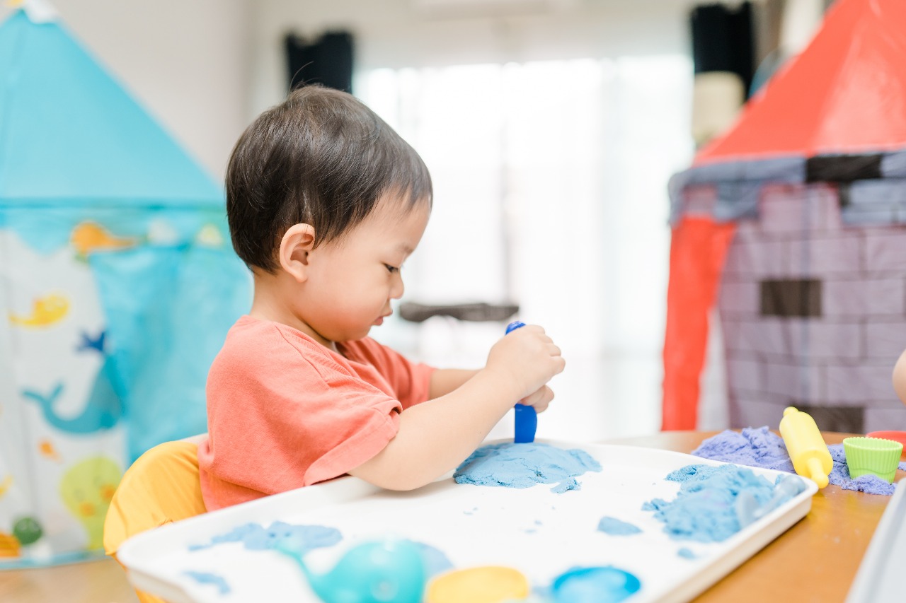 Child engaged in hands-on playdough activity, representing experiential immersive learning